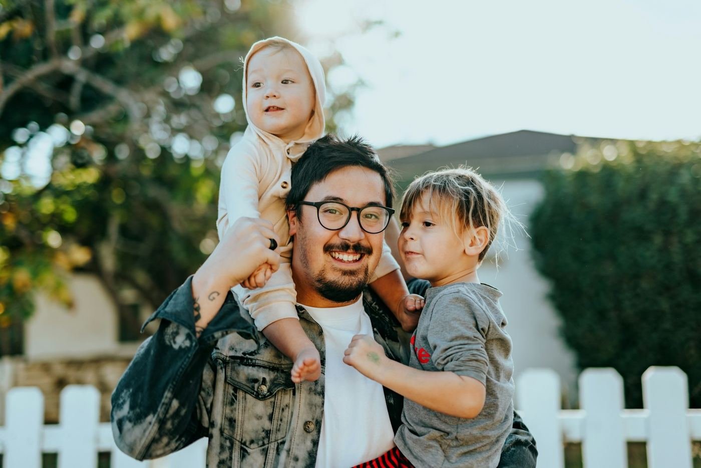 Smiling father with two kids outside their home